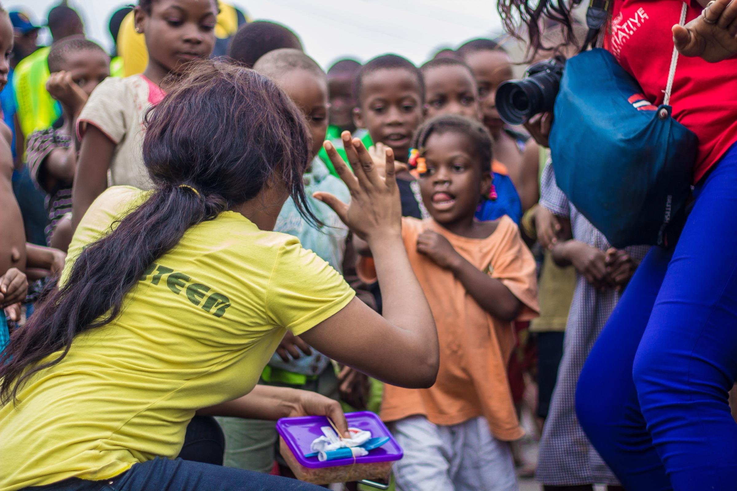 A volunteer high-fiving children gathered around her
